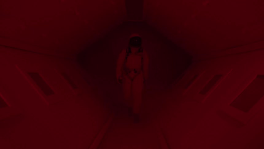 An astronaut walks down a futuristic red and purple lit hallway looking around with a sense of urgency