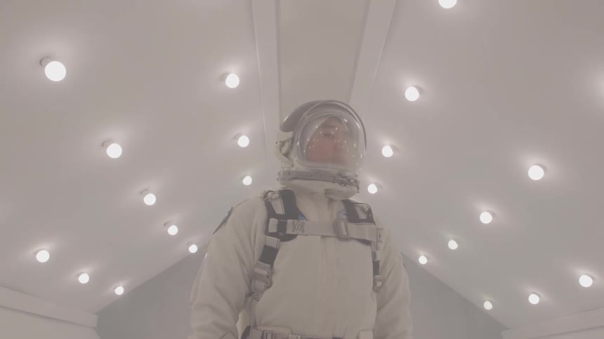 Astronaut in a spacesuit looks up at the illuminated ceiling