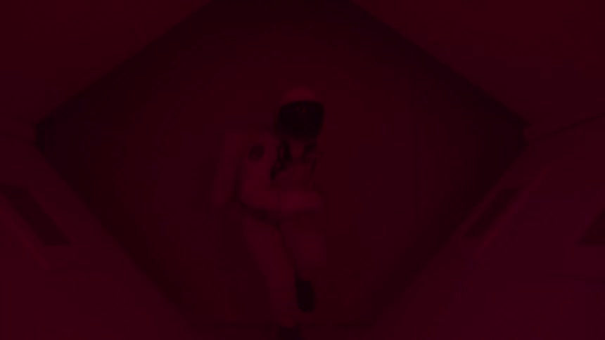 Person in spacesuit running down a hallway with flashing lights