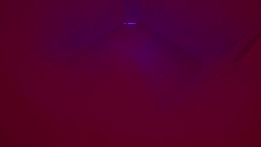 Person wearing a spacesuit running inside a spaceship surrounded by a foggy atmosphere with red emergency lights flickering