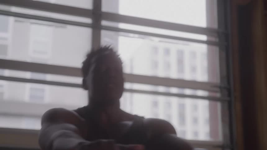 A black man is rowing fast on a rowing machine in a garage gym
