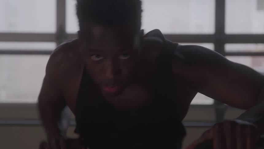 A man with an intense determined expression powers forward in the middle of a strenuous workout