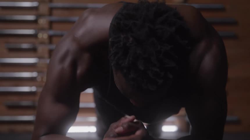 Close up of a young black man working out in a room during daytime