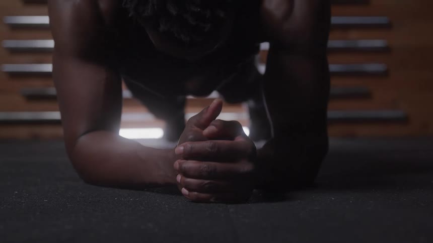A black young man doing plank exercise in a gym