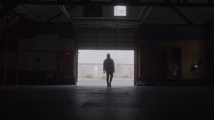 Silhouette of a young man standing while exercising indoors in a large room during daytime