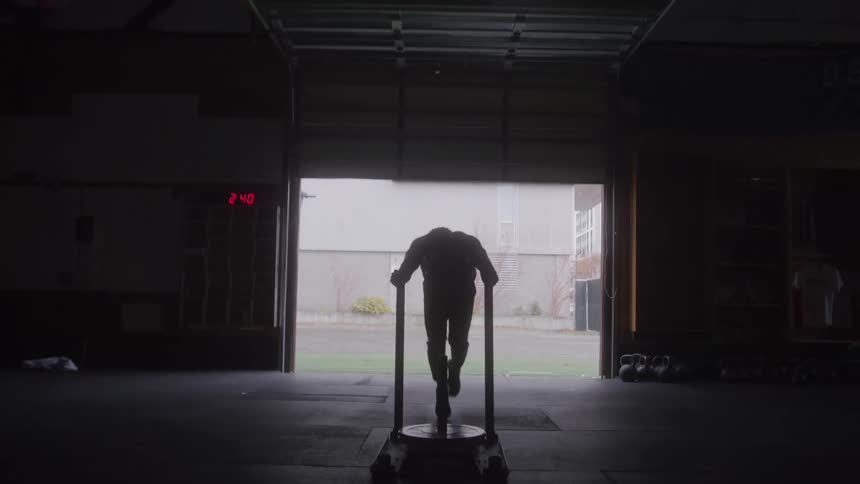 The man is pushing a cart with weights on it