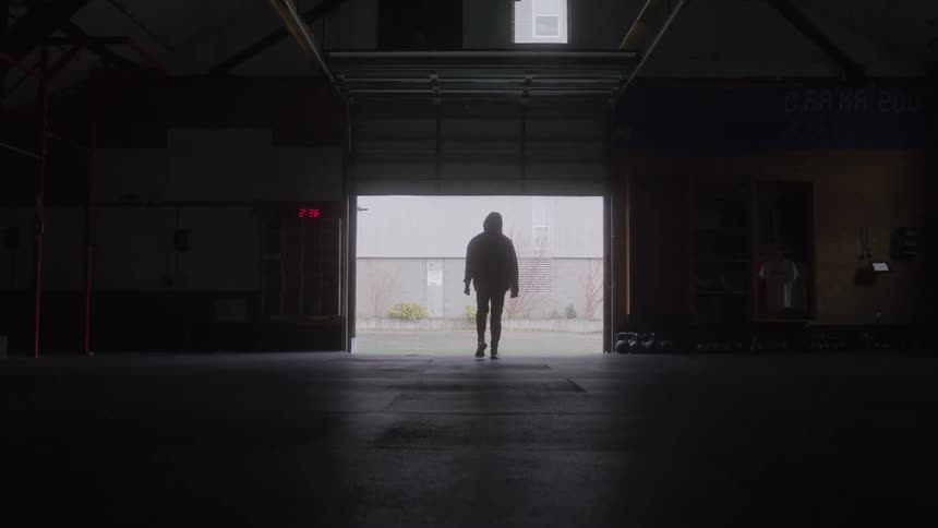 A young man walks outdoors to the entrance of a fitness room during daytime