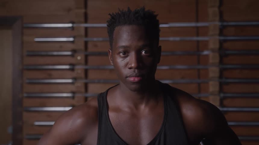 Close up portrait of a young black man standing in a room during a fitness session