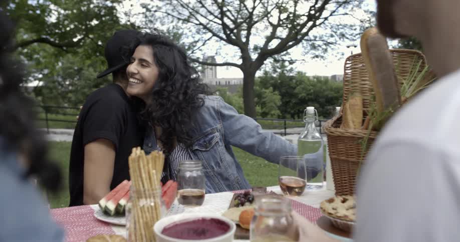 Group of men and woman laughing together outside at a picnic