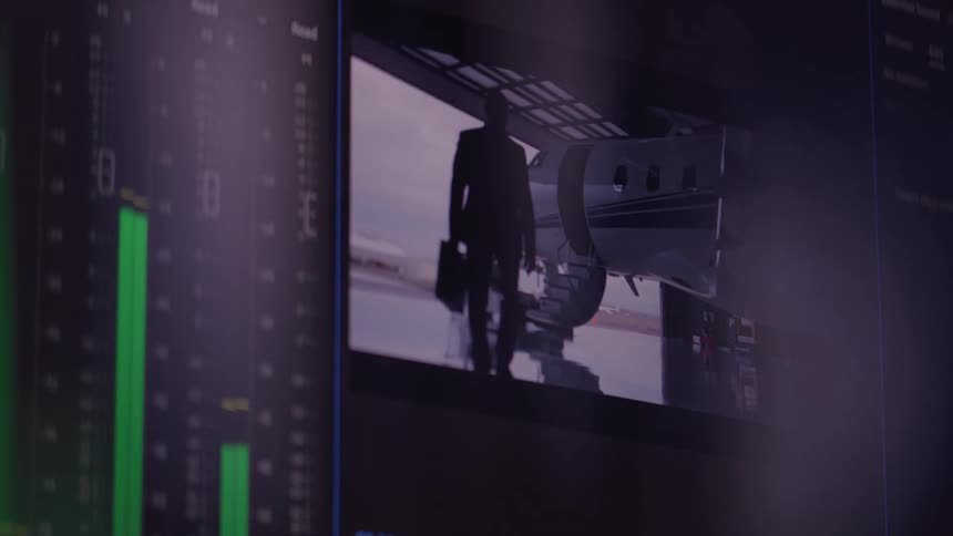 A video editing program is visible on a computer screen with various clips of landscapes cityscapes and people shown on the timeline and in a large viewing window