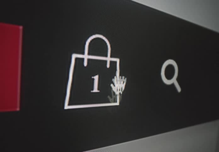 A closeup shot shows a computer screen with a black background the cursor hovers over a shopping bag icon with the number one inside indicating that an item has been added to the cart