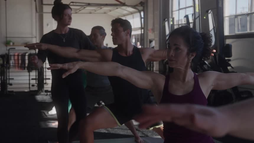 Pilates teacher correcting a student in a class
