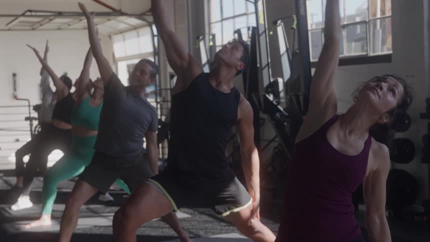 A group of people stretch together in a gym class