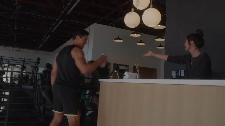 A man and a woman share a fist bump at a gym counter