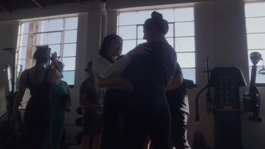 A group of people gather and hug inside a gym after a workout