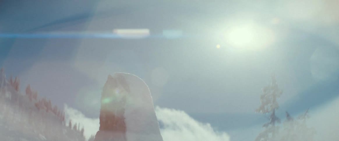 The camera pans across a rock formation in a mountain range with the sun in the background