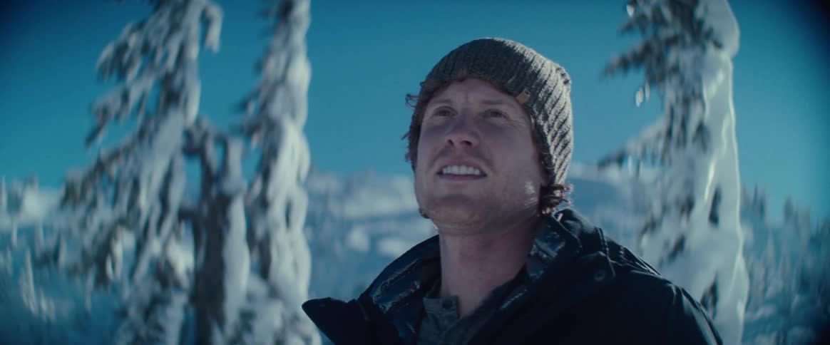 The man is smiling by the snow covered mountains