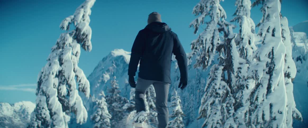 A person snowshoes through a snowy forest on a cold winter day