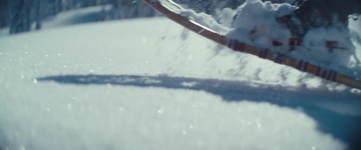 The clip shows a person snowshoeing through a beautiful snowcovered landscape the camera focuses on their feet as they trek through the deep snow with snowy trees and mountains visible in the background