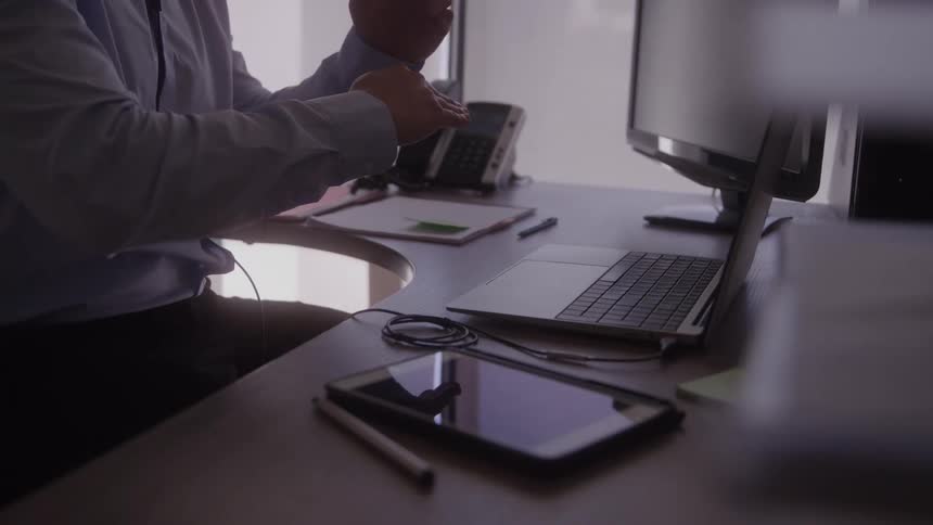 Person sitting at an office desk making hand gestures in front of the computer