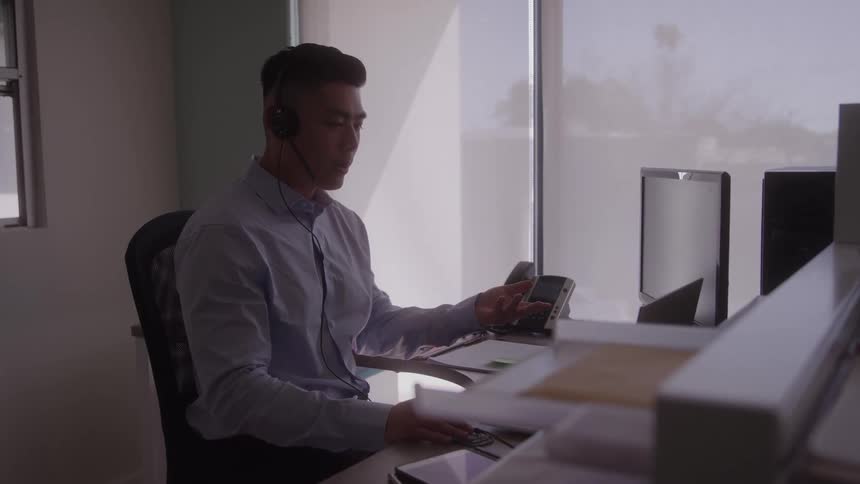 Man wearing headphones in a meeting while sitting at an office desk