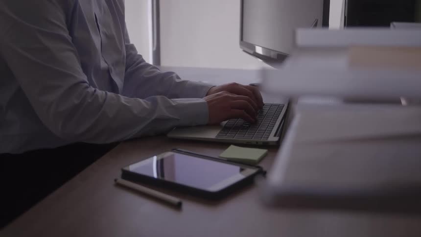 A person types on a laptop while seated at an office desk