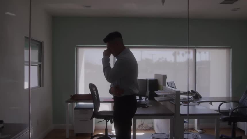 A man looks upset and overwhelmed by work stress in an office