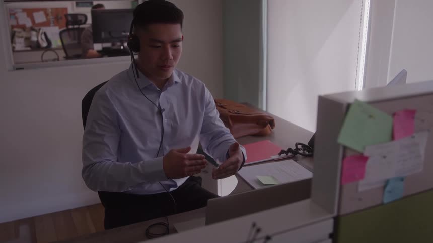 The man is talking and working in the office