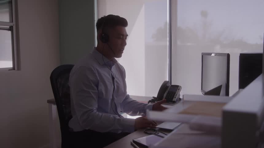 Man wearing a headset taking a call in an office