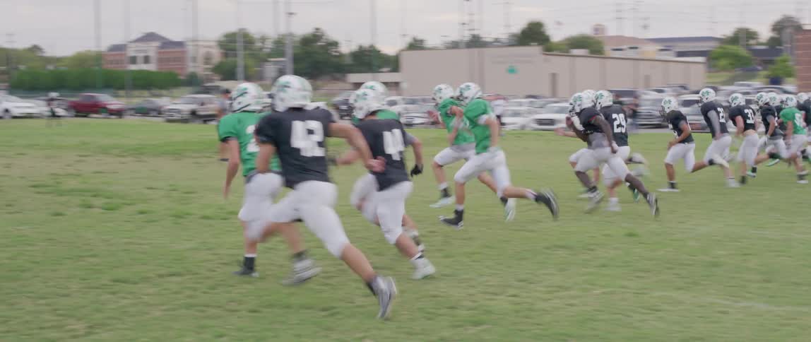 American football team running across a field in training
