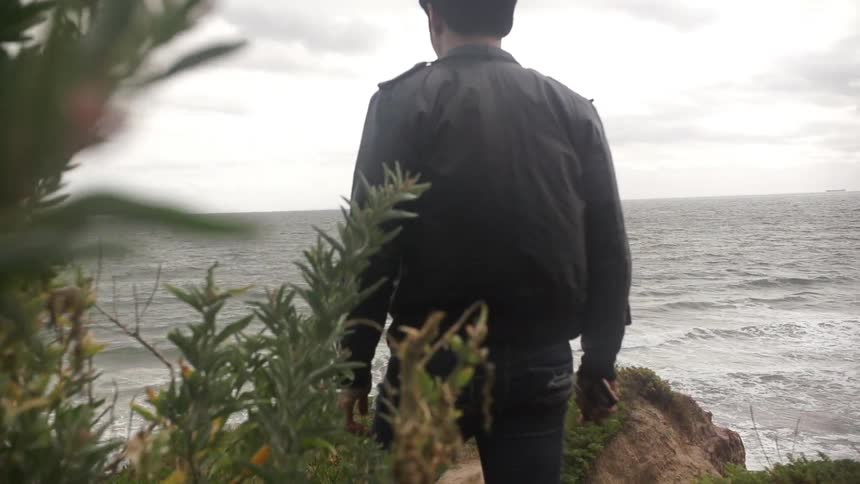 Man walking towards the water on a cloudy day