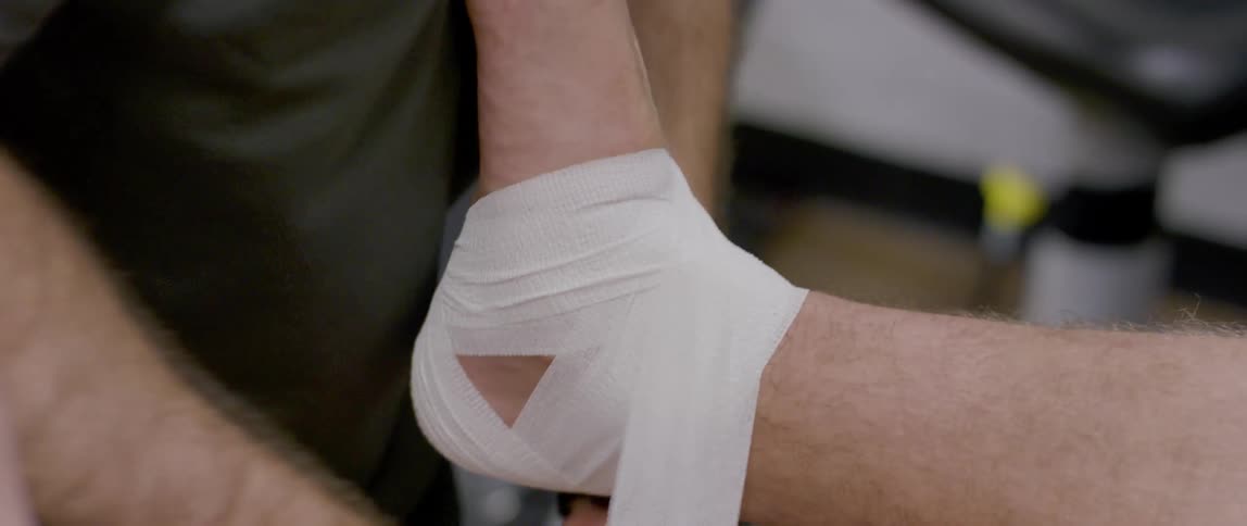 The man is taping up an injured ankle