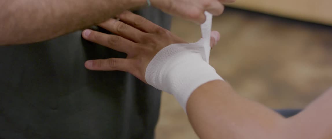 Person placing a bandage between another persons wrist and fingers