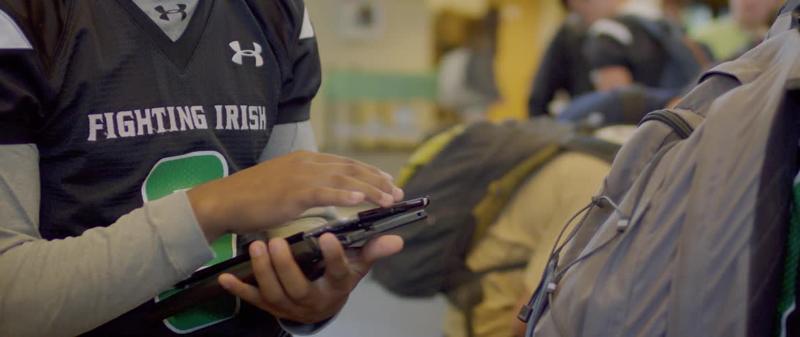 A football player is using a tablet in the locker room