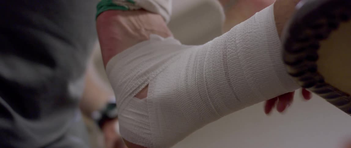 A man is taping up someones injured ankle