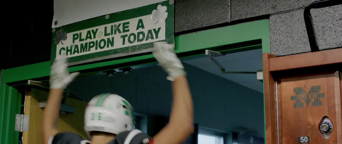 The video shows a football player wearing a helmet with the number 35 running out of a locker room a sign above the door reads play like a champion today