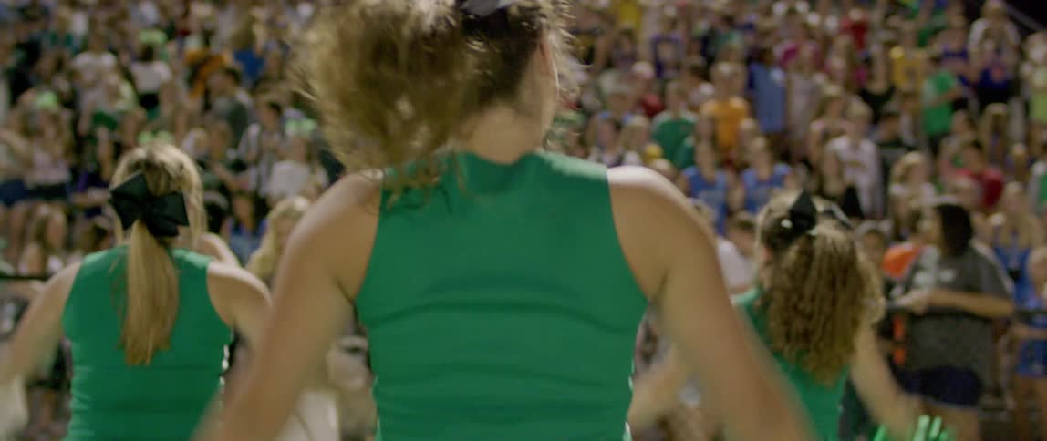 Cheerleader performing for the stadium crowd before a game with the audience visibly excited and energized