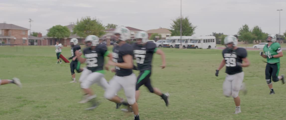 American football players running during practice on an open field
