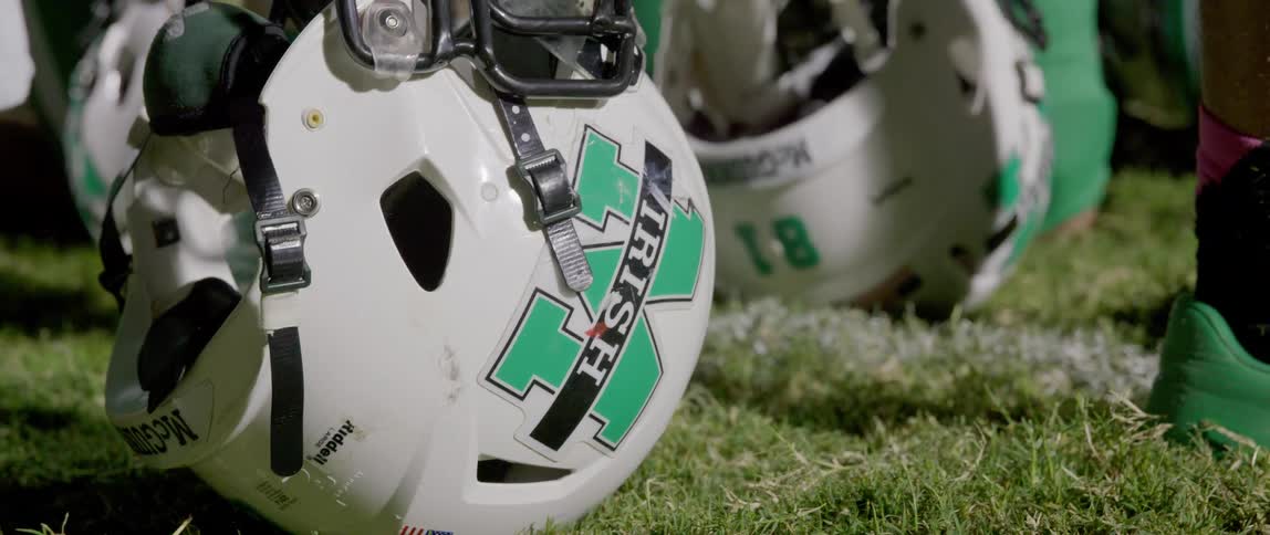 Series of football players helmets placed on the grass field