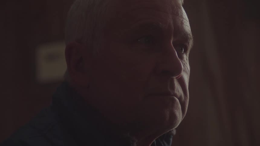 Elderly man sitting indoors looking sad and alone