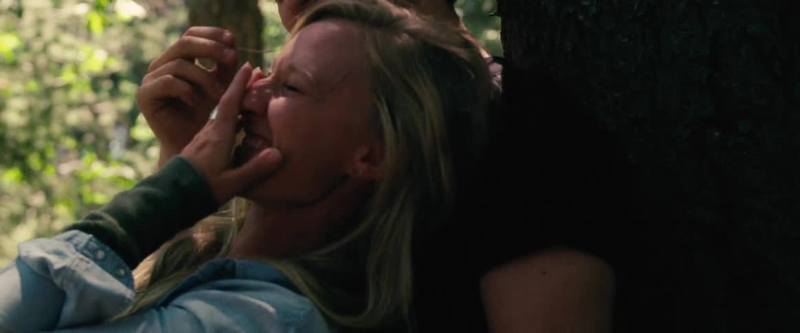 A woman laying on a man in the woods laughing