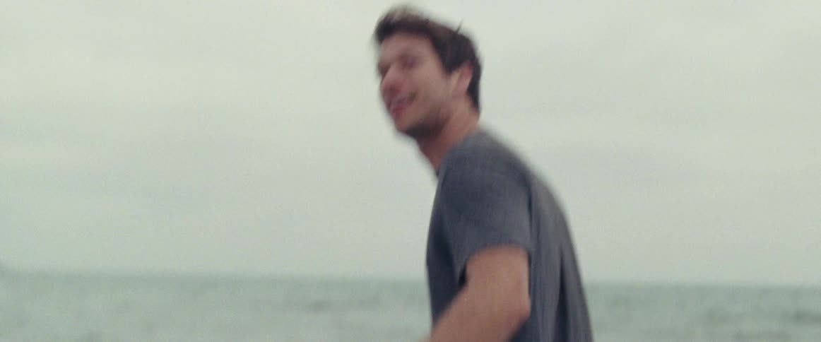 Smiling man walks in the water at the beach