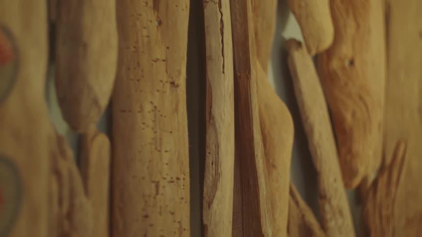 A medium shot of an art piece made of several long thin pieces of driftwood the wood is a mix of tan and brown tones with varying textures