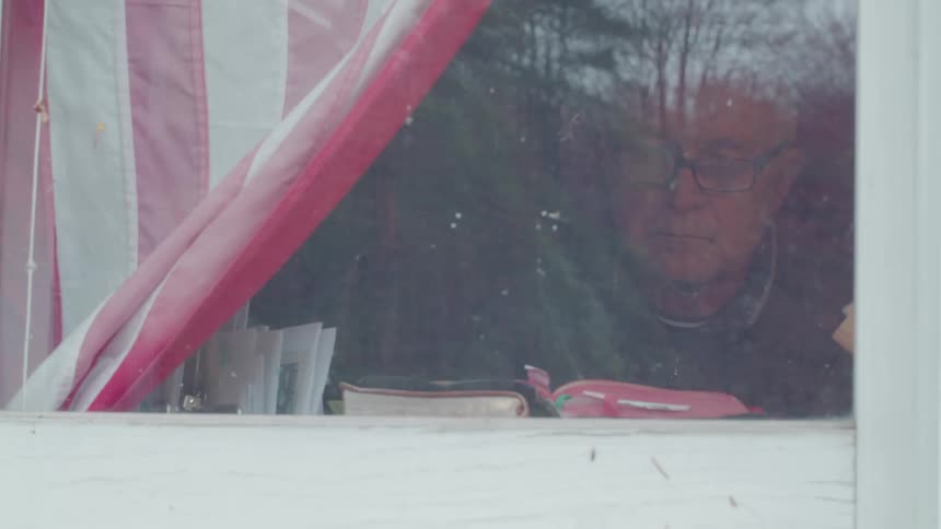 Man sitting in the window leafing through a bible