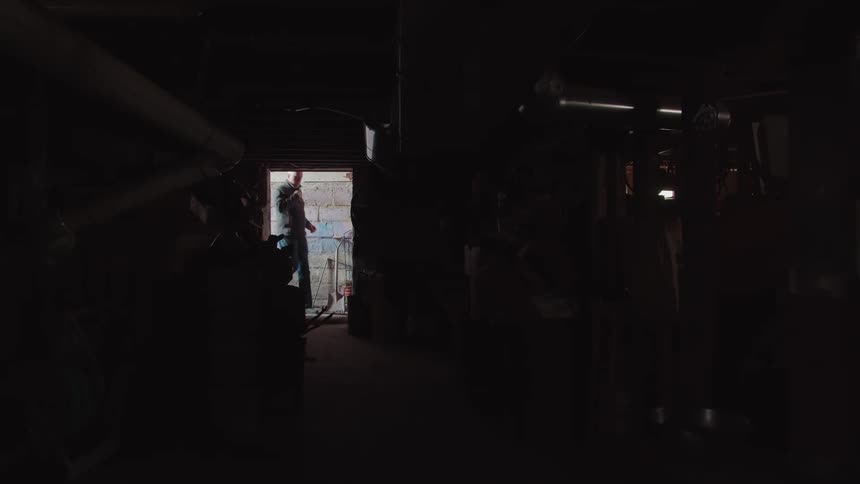Man standing at the bright entrance of a dark warehouse