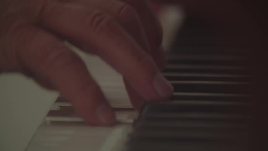Closeup of a hand playing piano keys