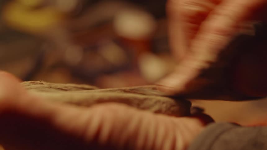 Hands of a male carpenter polishing a piece of wood indoors