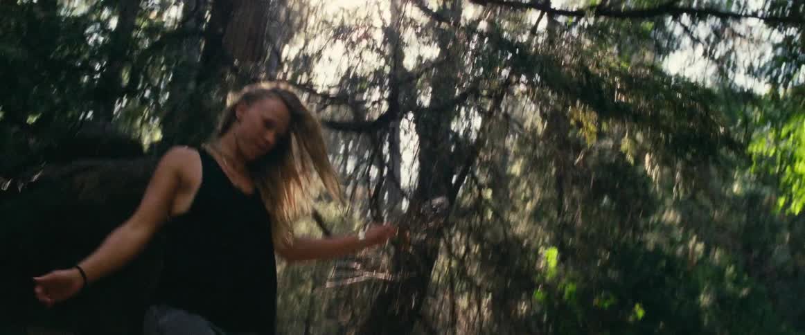 Woman balances and walks through the woods on a sunny day