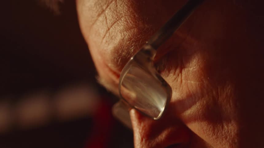 Extreme close up of a man wearing reading glasses in a room