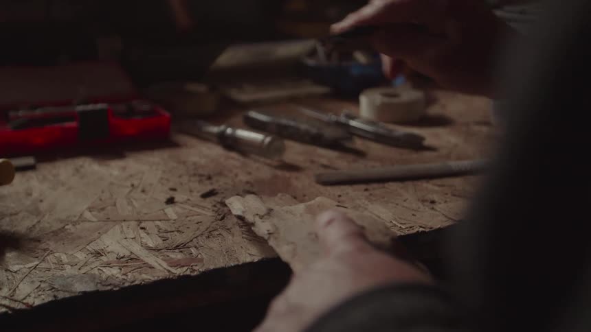 A person is carving a piece of wood they use a knife to shave off thin pieces from a stick